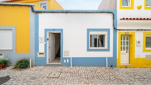Um edifício com chão de pedras, uma porta e uma janela.