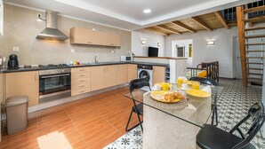 Cozinha moderna com armários de madeira, forno embutido, máquina de lavar e área de refei ções com itens de café da manhã.