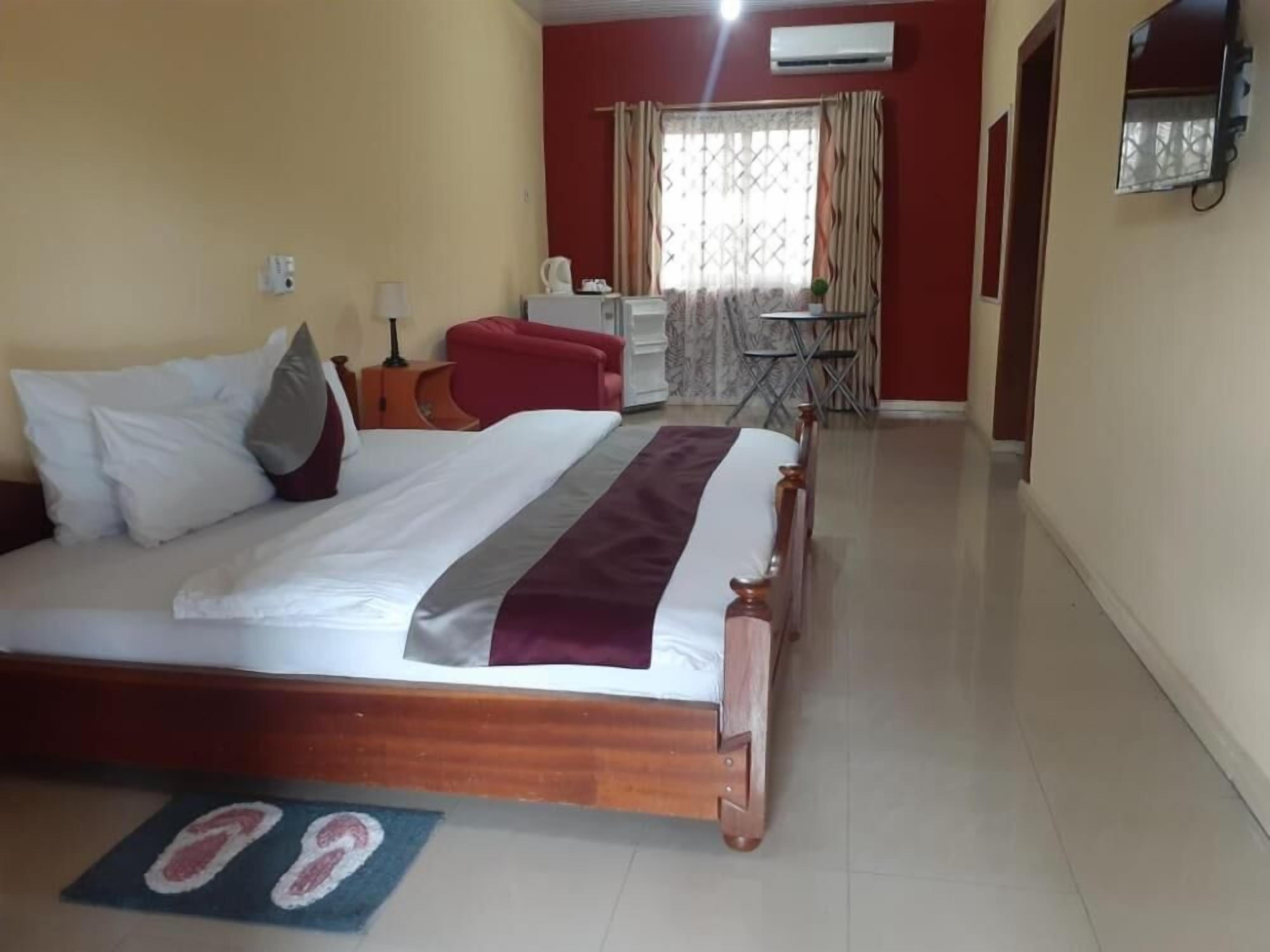 Una habitación de hotel con cama, escritorio, silla y una mesita.