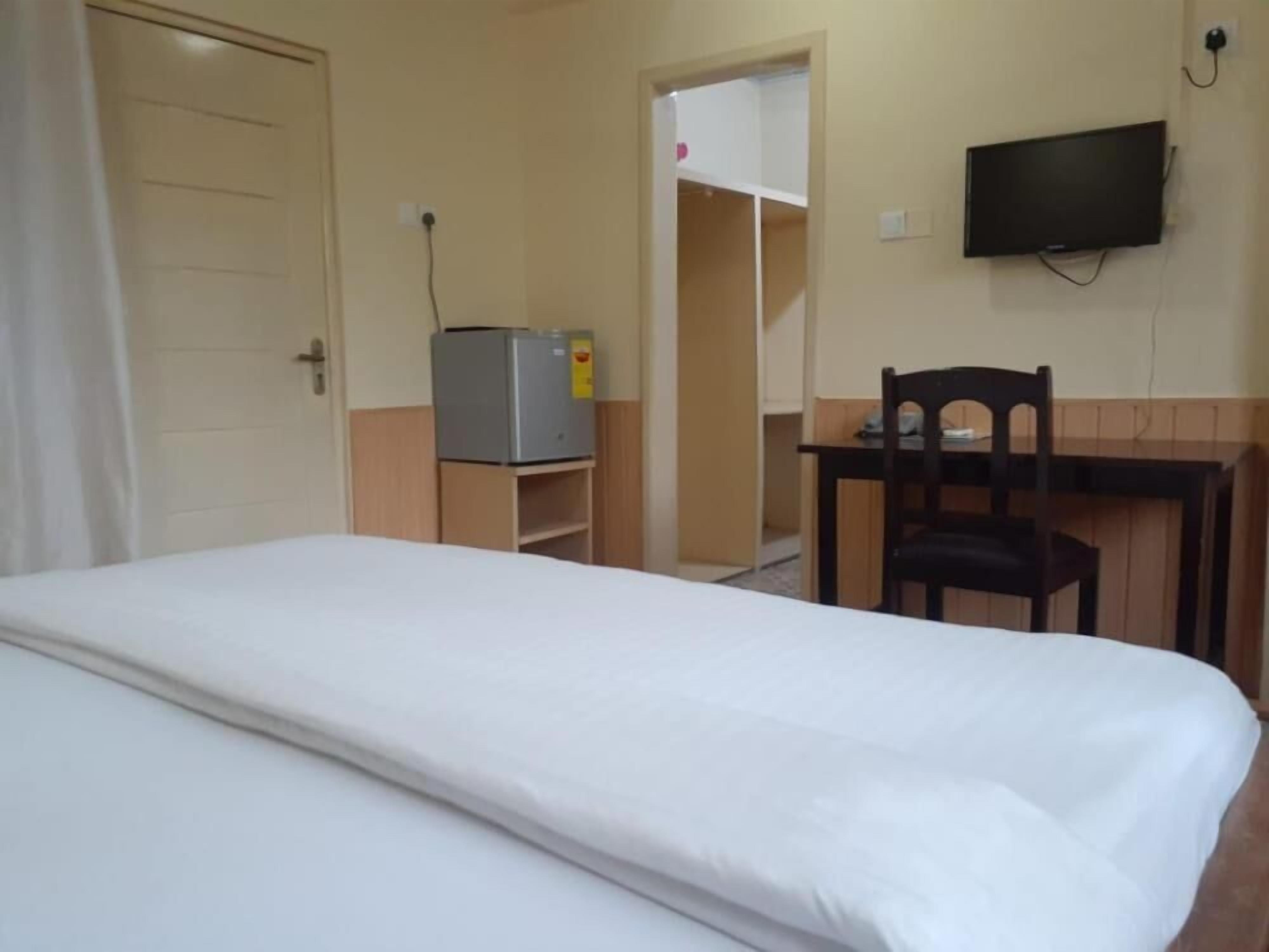 A room with a bed, a desk, a chair, a television, and a wardrobe.