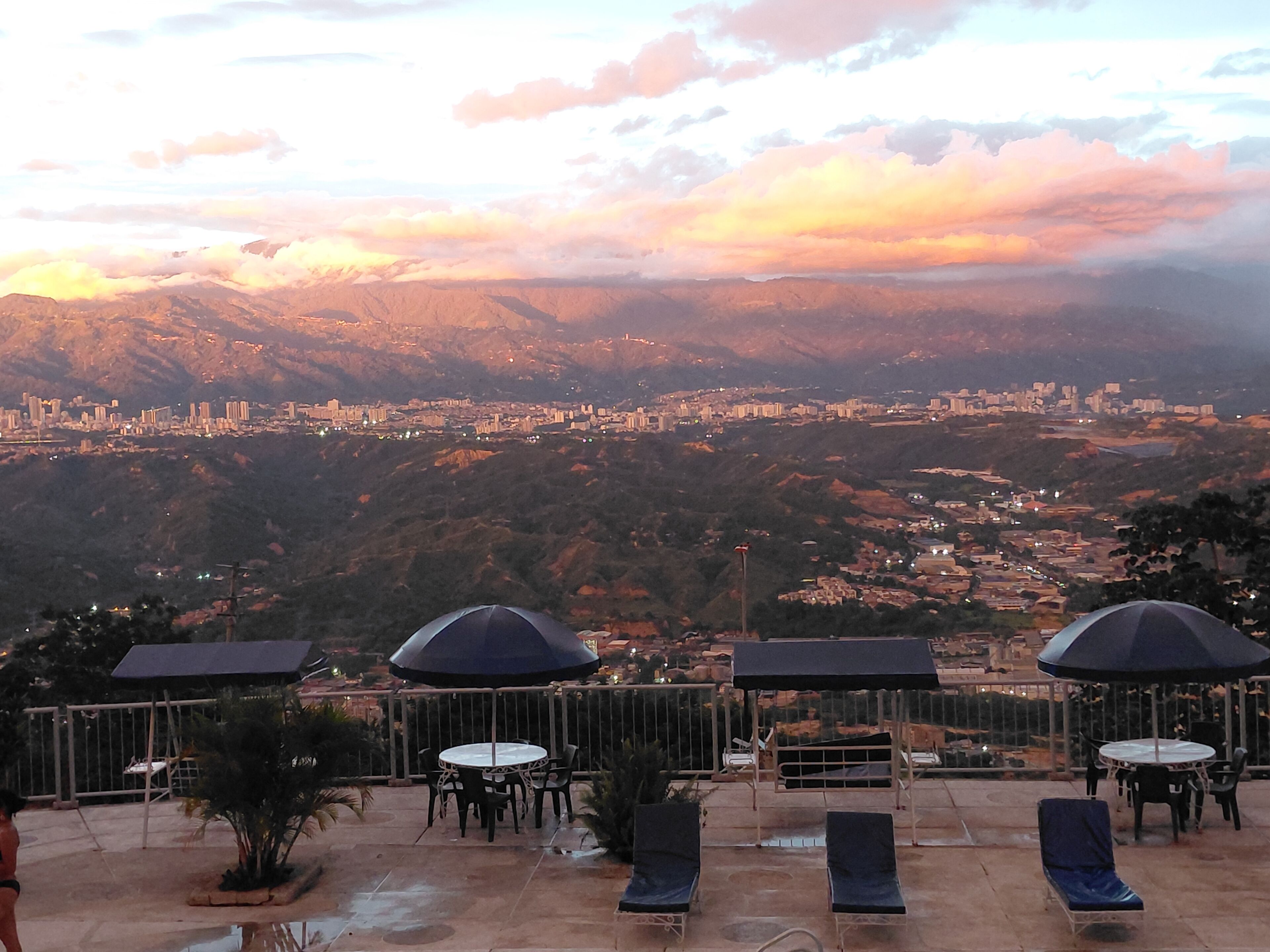 Eine Terrasse mit Sitzgelegenheiten und Blick auf eine Stadtlandschaft und Berge.