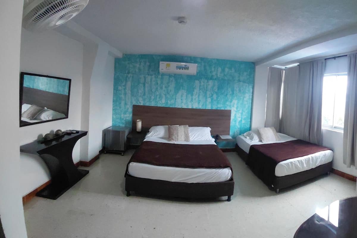 Une chambre d’hôtel avec deux lits, une table de chevet, une chaise, un bureau, un miroir et une fenêtre avec des rideaux.