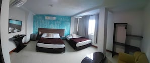 Habitación de hotel con dos camas, una mesita de noche, una silla, un escritorio, un espejo y una ventana con cortinas.