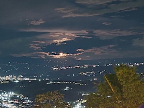 Une vue nocturne d’une ville, avec des lumières lointaines et un ciel nuageux.