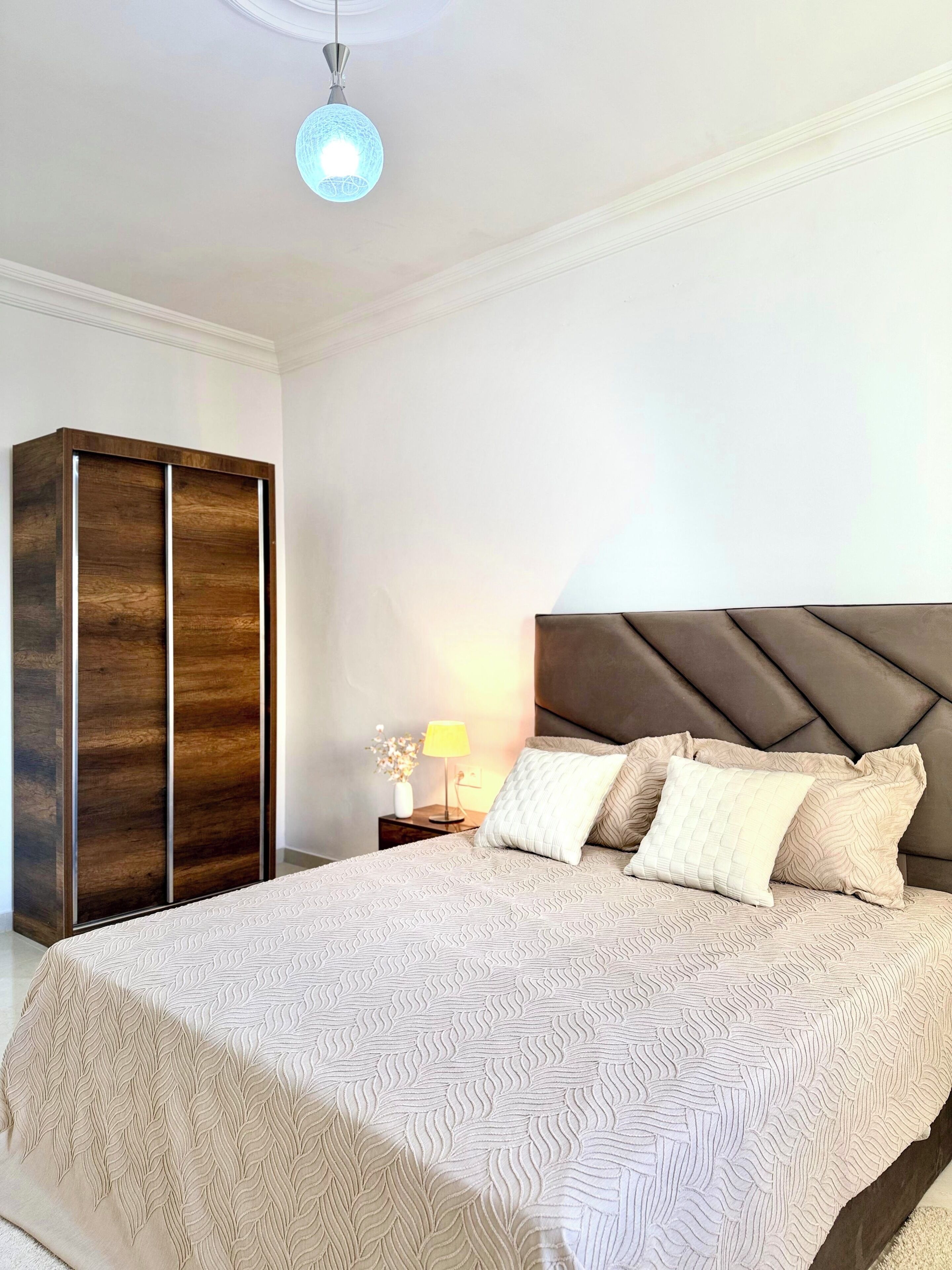 Una camera da letto con un letto, un comodino, una lampada e un armadio.