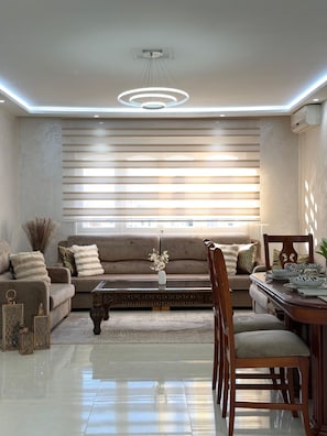A modern living room with a sofa, coffee table, and dining area. - 3-bedroom apartment in peaceful Tangier (Tangier)