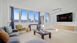 Ein modernes Wohnzimmer mit einer Couch, einem Couchtisch und einem an der Wand befestigten Fernseher.
