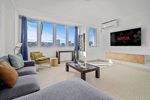 Ein modernes Wohnzimmer mit einer Couch, einem Couchtisch und einem an der Wand befestigten Fernseher.