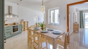 A modern kitchen with a dining area, stainless steel appliances, and a wooden dining table set for four. - Charming bright penthouse with 3 Terraces JCUT2-1 (Swieqi)