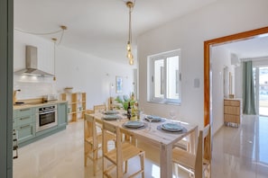 A modern kitchen with a dining area, stainless steel appliances, and a wooden dining table set for four. - Charming bright penthouse with 3 Terraces JCUT2-1 (Swieqi)