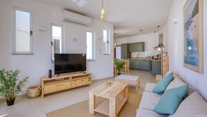 A living room with a television, sofa, coffee table, and a kitchen in the background. - Charming bright penthouse with 3 Terraces JCUT2-1 (Swieqi)
