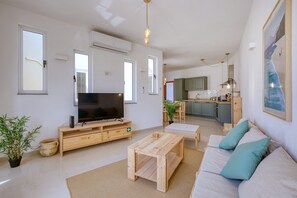 A living room with a television, sofa, coffee table, and a kitchen in the background. - Charming bright penthouse with 3 Terraces JCUT2-1 (Swieqi)