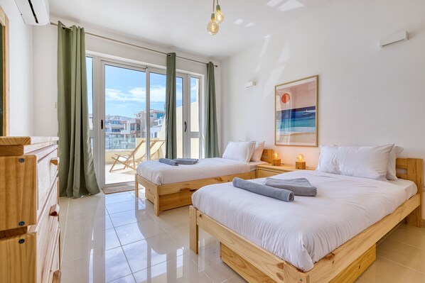 A hotel room with two wooden beds, a large window with curtains, a chair outside, and a painting on the wall. - Charming bright penthouse with 3 Terraces JCUT2-1 (Swieqi)