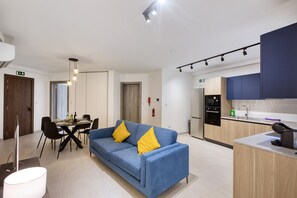 Ein modernes Wohnzimmer mit Sofa, Esstisch und Küchenbereich.