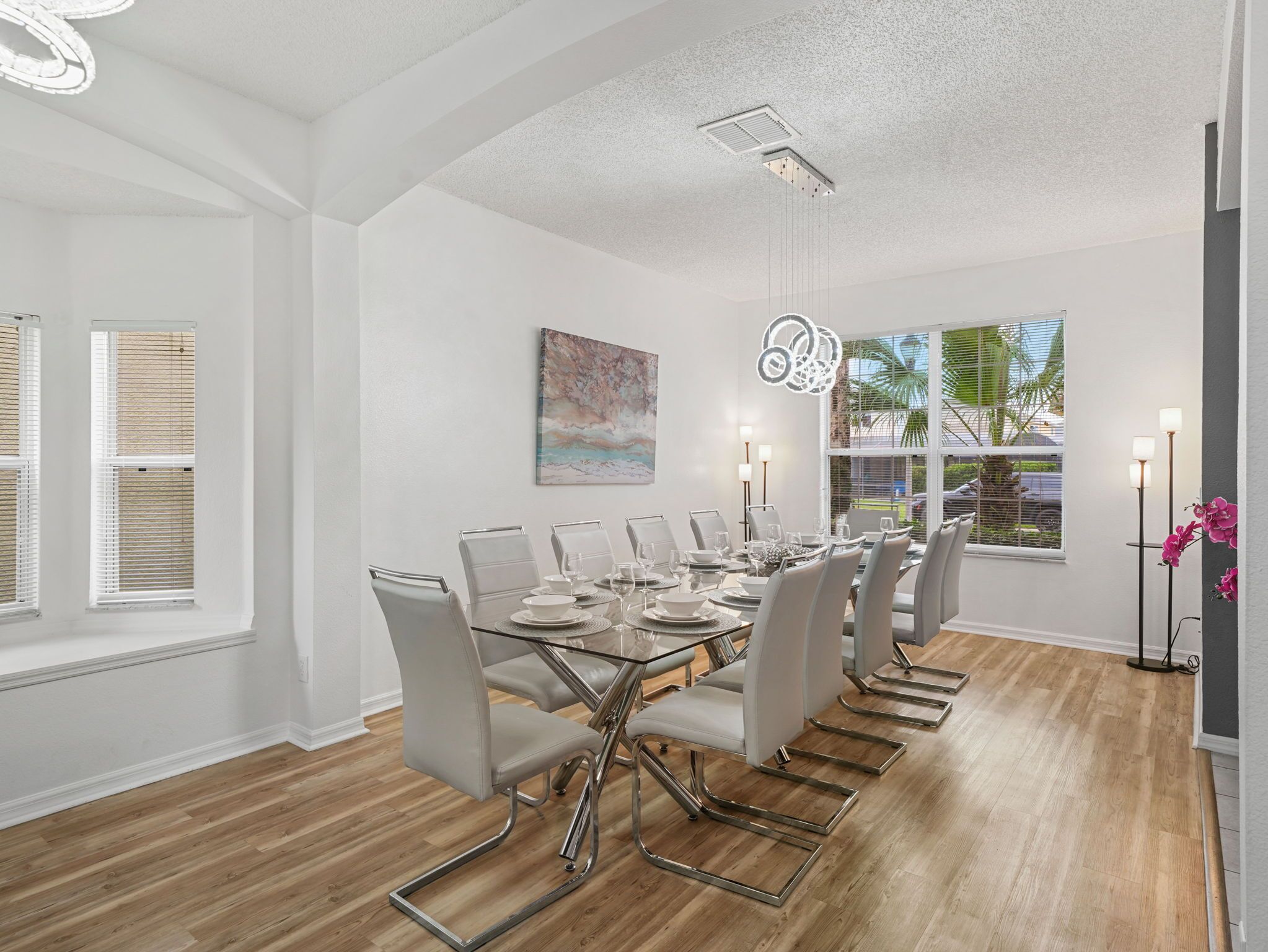 A dining room with a long table, chairs, and a ceiling light fixture.