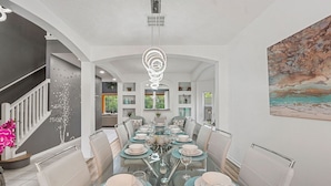 Un comedor con una mesa de vidrio, sillas y una lámpara decorativa en el techo.