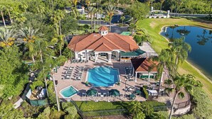 Un resort con una amplia piscina, varias zonas de descanso y vistas a un lago.