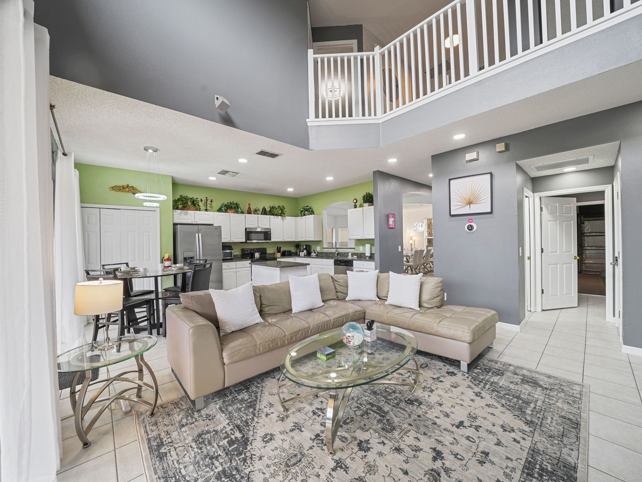 A spacious living room with a sectional sofa, a glass coffee table, and a dining area with a glass table.