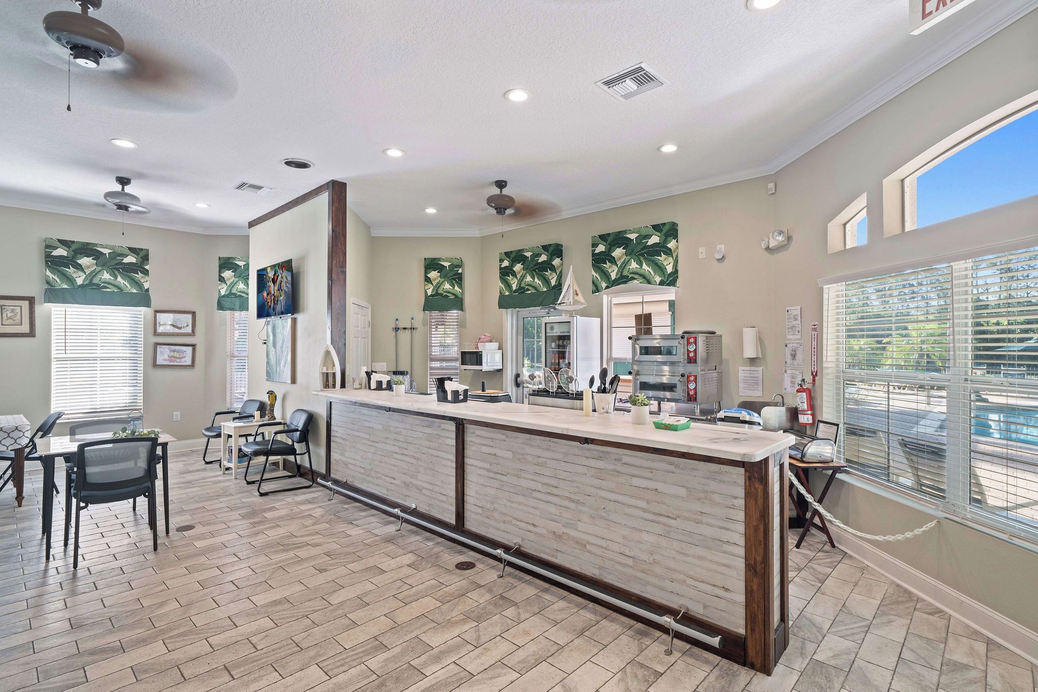 A spacious kitchen with a long counter, modern appliances, and a view of the street.