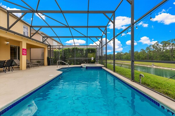 A swimming pool with a covered area, a hot tub, and a view of a water channel. - 8579 La Isla Drive (Kissimmee)