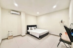 A bedroom with a bed, bedside table, chair, and an air conditioning unit. - Priority Kalimantan Samarinda (Samarinda)