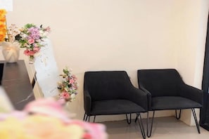 Una habitación con dos sillas negras, una pizarra decorada con motivos florales y un jarrón con flores.