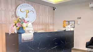 A reception desk with a marble top, a large sign with 'PRIORITY' and a stylized 'P', and a vase with flowers. - Priority Kalimantan Samarinda (Samarinda)