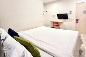 A hotel room with a bed, a desk, a chair, a television, and a door. - Priority Kalimantan Samarinda (Samarinda)