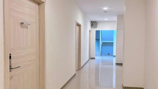 A corridor with a wooden door, a tiled floor, and a blue wall in the distance. - Priority Kalimantan Samarinda (Samarinda)