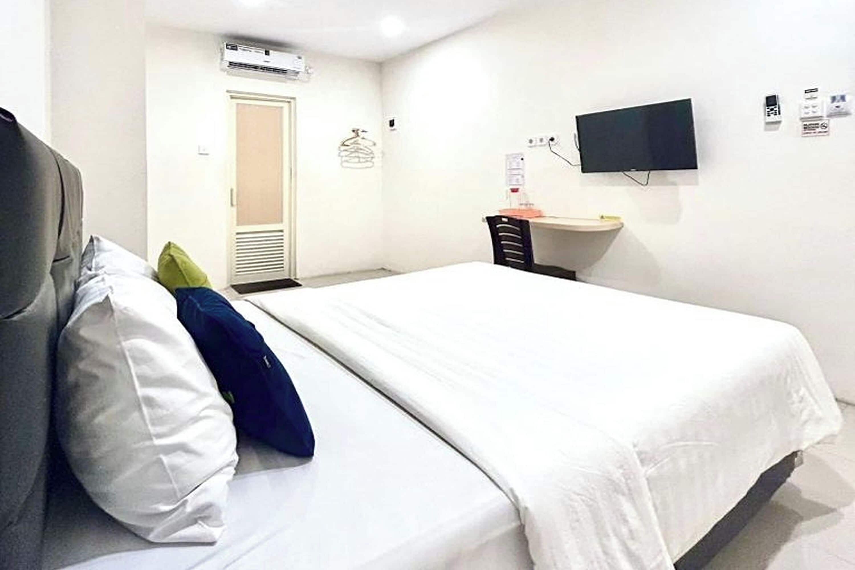 Una habitación de hotel con una cama, un escritorio, una silla, un televisor y un aire acondicionado.