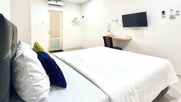Una habitación de hotel con una cama, un escritorio, una silla, un televisor y un aire acondicionado.