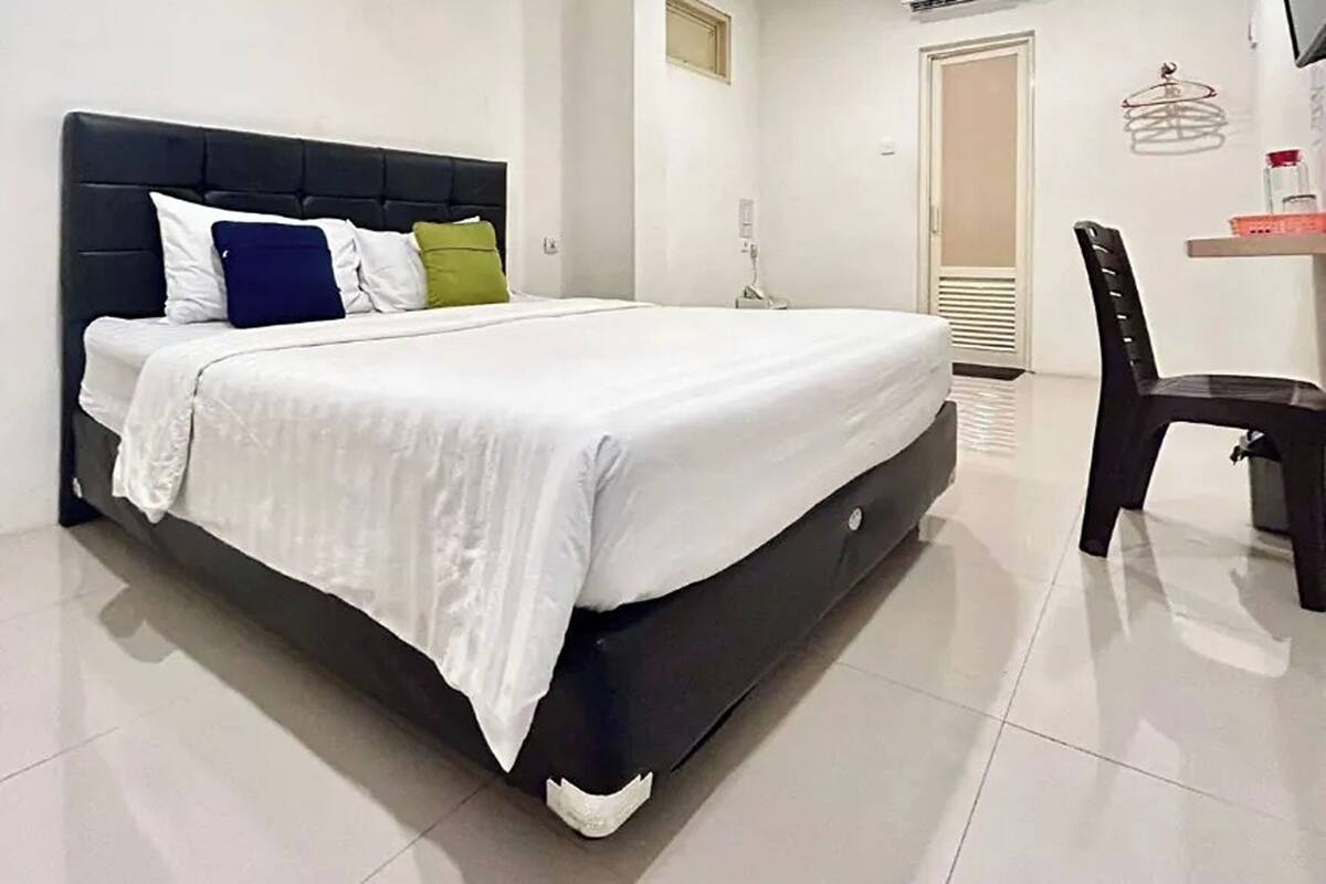 A bed with a dark headboard, white bedding, and multiple pillows.