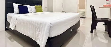 A bed with a dark headboard, white bedding, and multiple pillows.