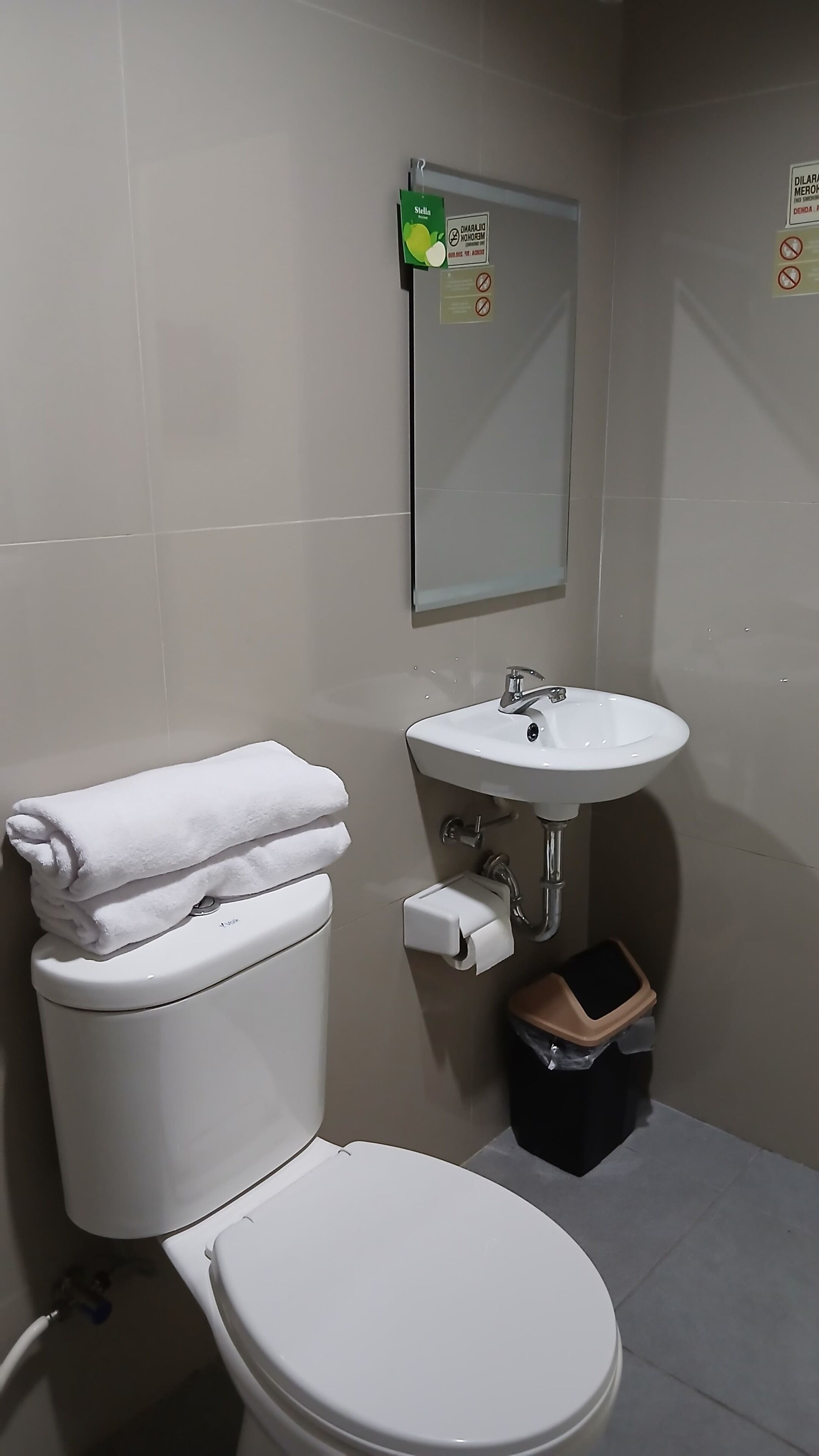 Un baño con inodoro, lavamanos y un cesto de basura.