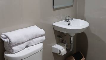 Un baño con inodoro, lavamanos y un cesto de basura.