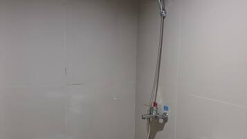 A bathroom with a toilet, a shower, and a towel rack.