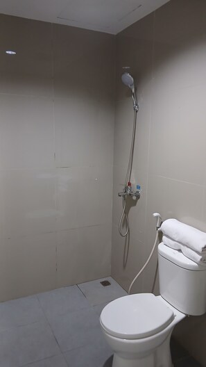 A bathroom with a toilet, a shower, and a towel rack. - Priority Teuku Umar Samarinda (Samarinda)