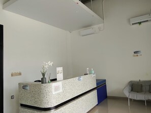 A reception desk with a sign, a potted plant, and a blue counter. - Priority Teuku Umar Samarinda (Samarinda)