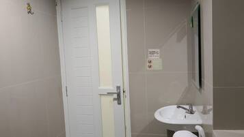 Un baño con una puerta blanca, un lavabo y un perchero para toallas.
