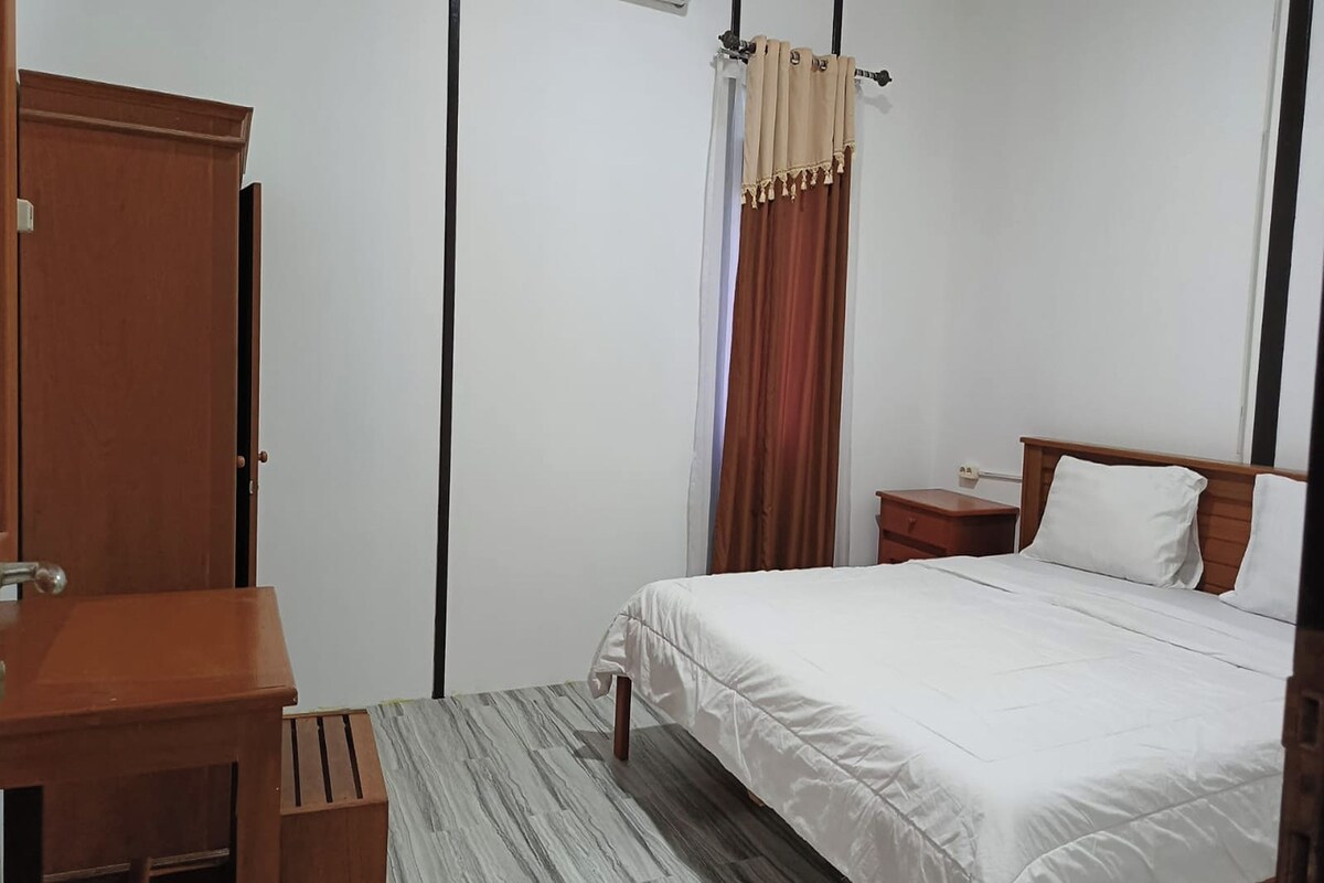 Une chambre d’hôtel avec un lit, une table de chevet et une armoire en bois.