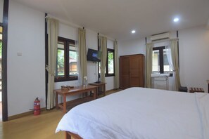 Une chambre d’hôtel avec un lit, une télévision, un bureau et une armoire.