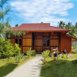 Une maison en bois avec un toit en tuiles, entourée de verdure et de palmiers.