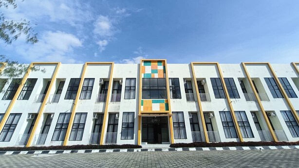 Un edificio de varios pisos con una entrada central, ventanas amplias y una fachada con diseño.