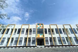 A multi-story building with a central entrance, large windows, and a patterned facade.