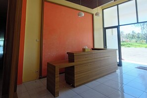A reception desk with a bench, a large window, and a door with a red wall.