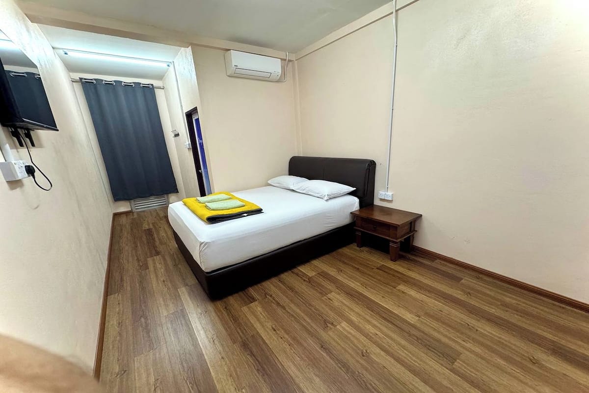 Un dormitorio con cama, mesita de noche y unidad de aire acondicionado.
