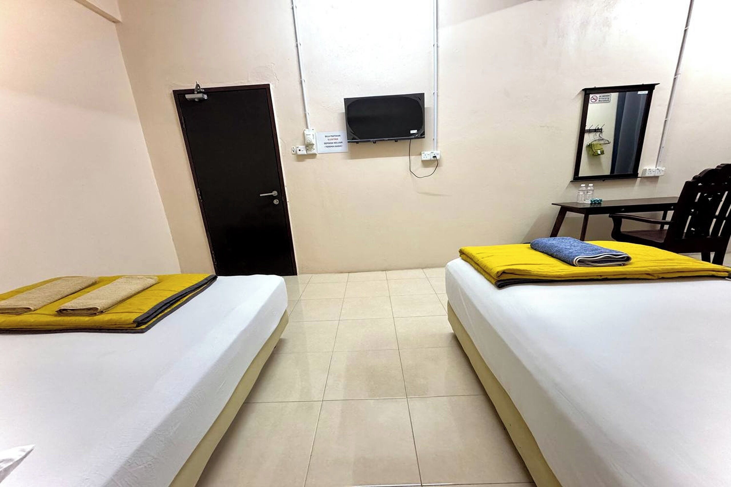 Une chambre d’hôtel avec deux lits, une télévision, un bureau, une chaise et une porte.