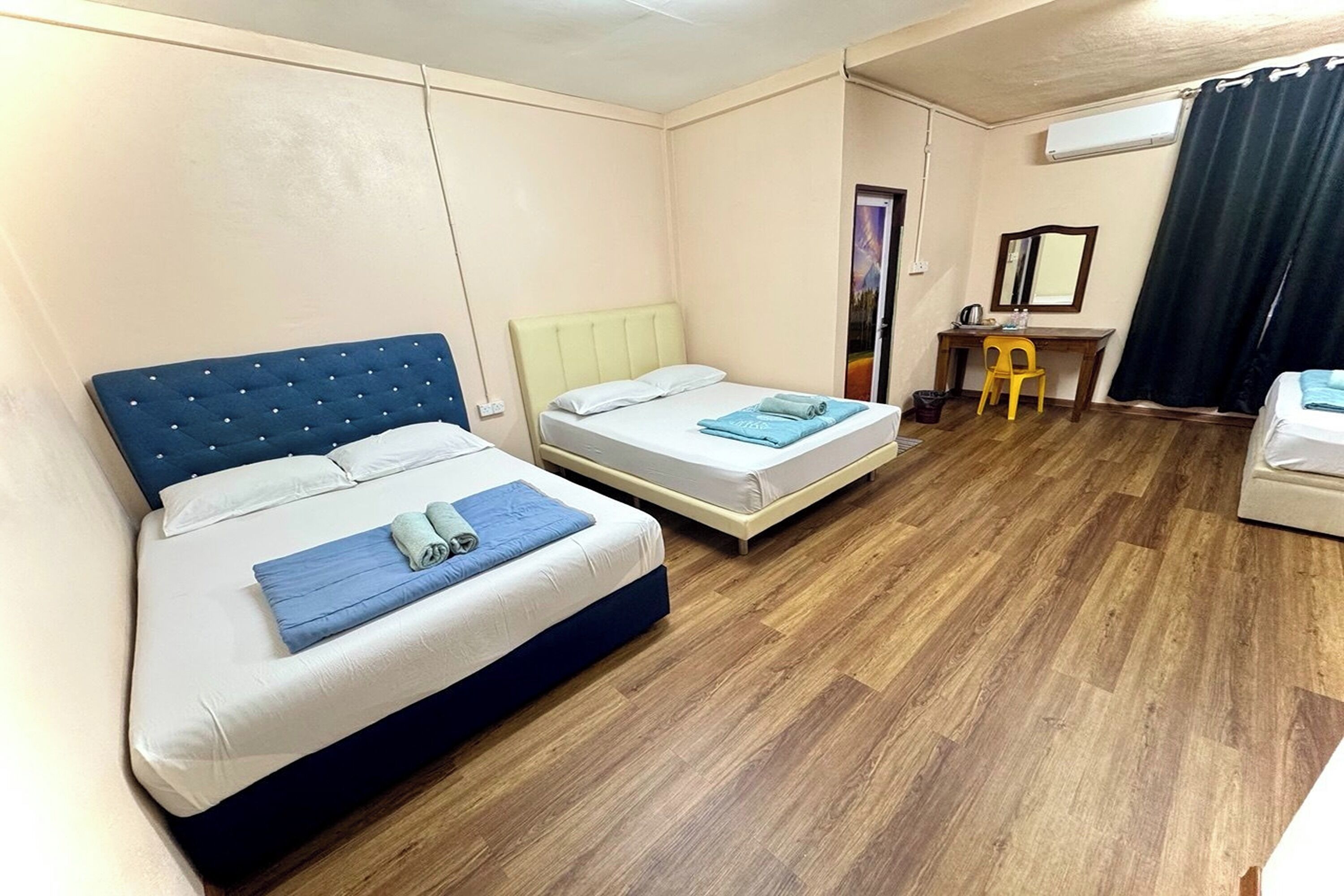 A hotel room with two beds, a desk, a chair, and a mirror.