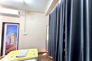 Ein Hotelzimmer mit Bett, einem Fenster mit Blick auf ein Gebäude, einer Klimaanlage und einem Vorhang.