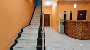 A hotel lobby with a staircase, reception desk, and a wooden reception area. - Hotel Rs Inn (Pasir Mas)